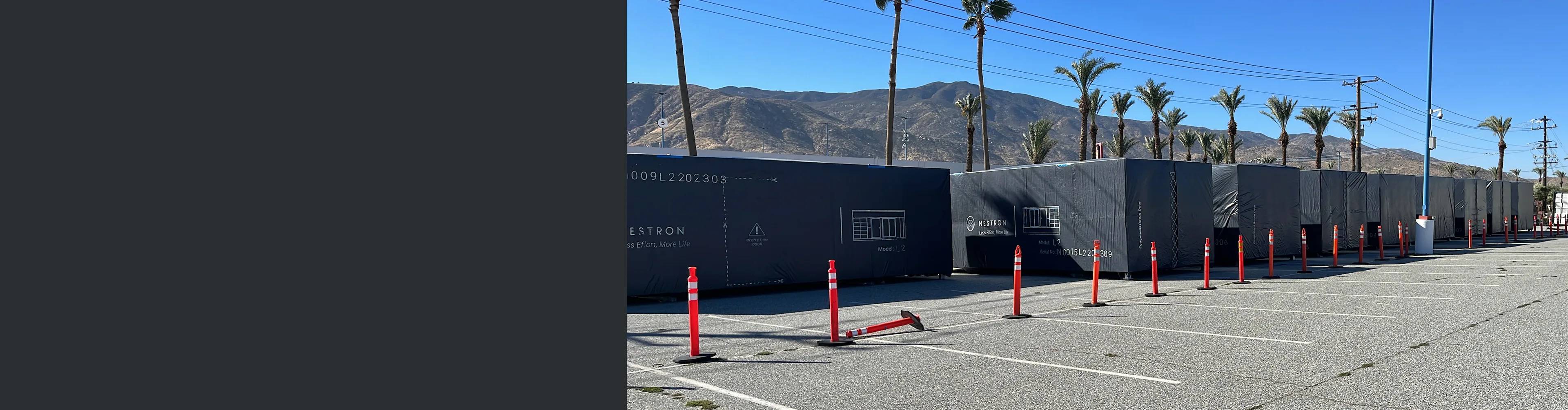 Exterior view of a dark modular building with mountain scenery and safety bollards in the foreground