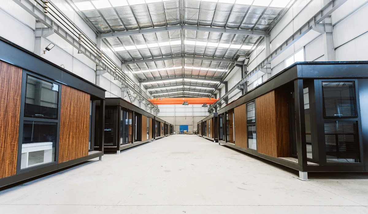 Interior of a modular home production facility with units lined up along a factory floor