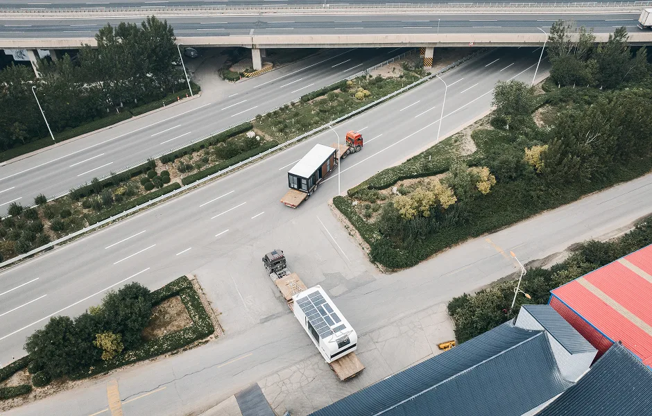 Aerial view of trucks transporting modular home units along a roadway