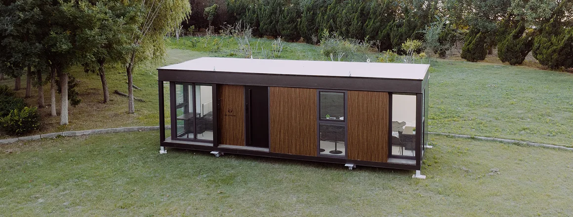 Exterior view of a modern modular home with wood siding, dark trim, and large windows