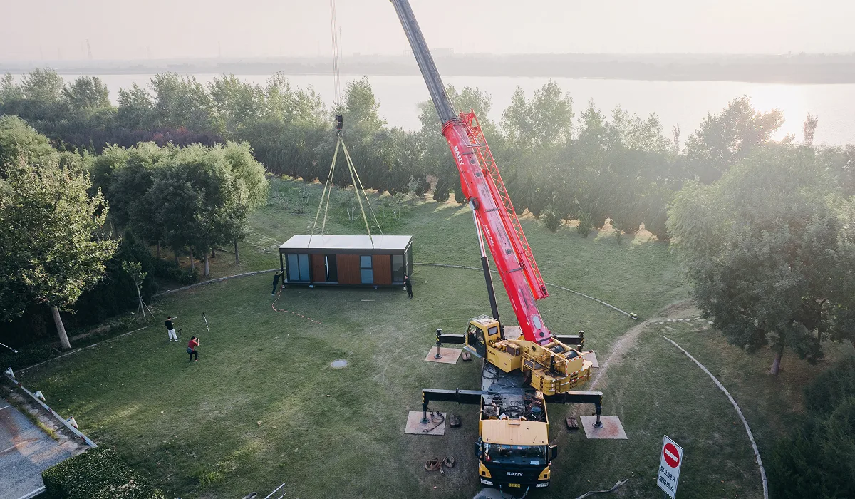 Crane installing a modular home unit at a wooded site