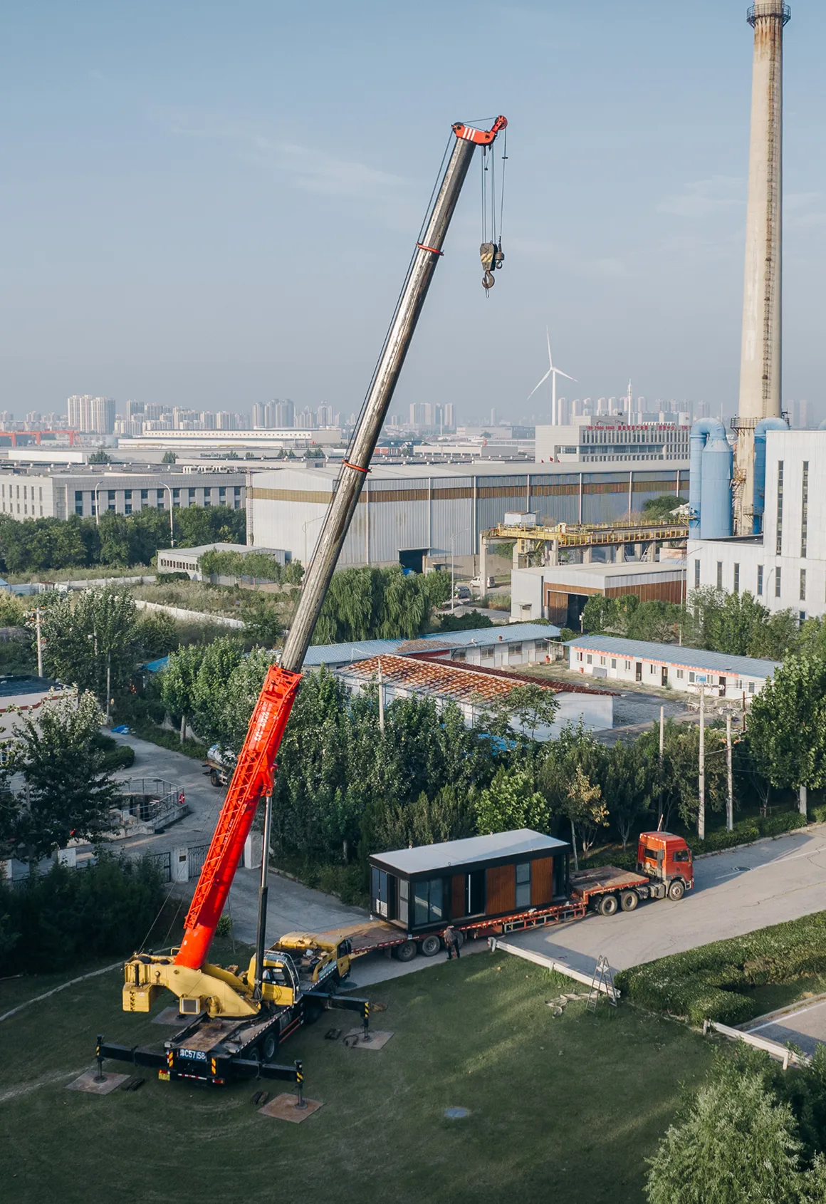 Crane lifting a modular home unit during installation at a developed site