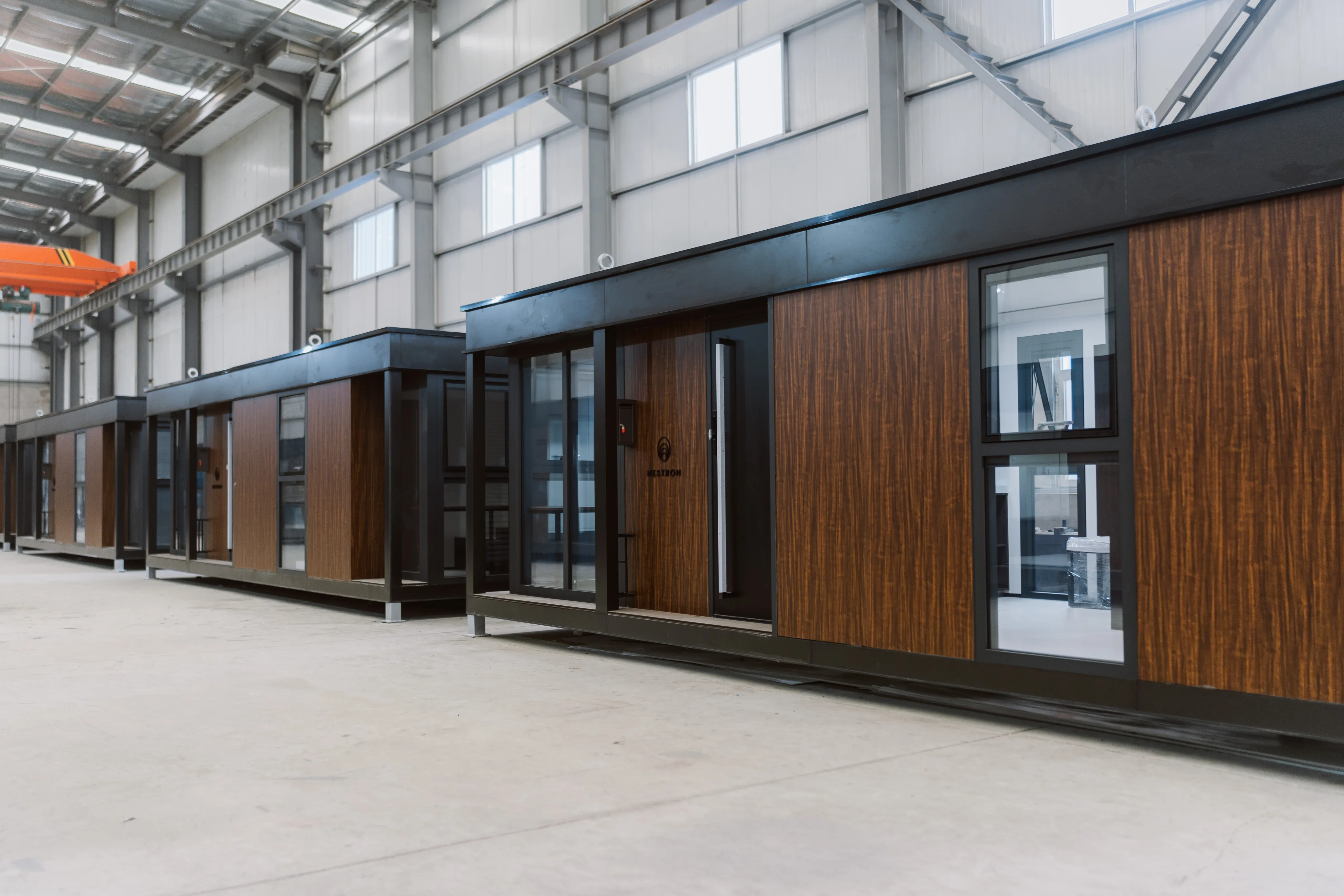 Nestron modular homes with wood paneling lined up inside factory warehouse