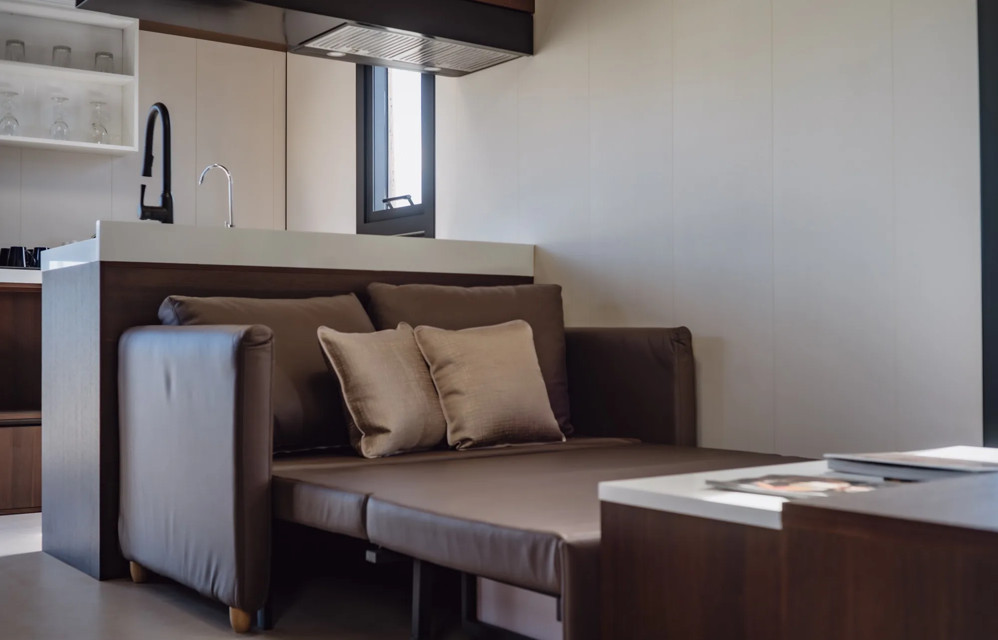 Nestron modular home living room with brown sectional sofa and kitchen counter